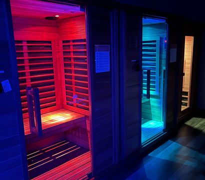 Infrared sauna cabins in a spa, glowing red, blue and teal LED light over wooden benches
