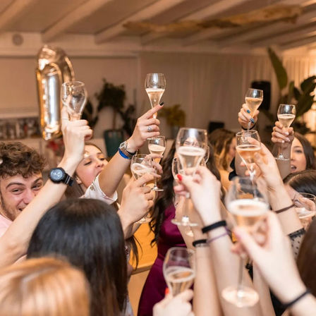Cheers! Group of friends raising champagne flutes in a lively indoor celebration and toast