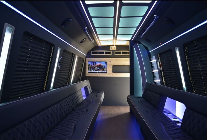 Sleek luxury party-bus interior with opposing quilted leather benches, neon-blue LED accents, illuminated ceiling panels, wall-mounted TV and cup holders.