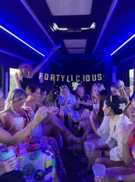 Group of women celebrating a 40th birthday aboard a neon-blue party bus, holding drinks under a FORTYLICIOUS banner