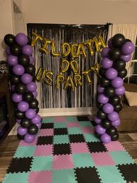 Indoor party backdrop with black fringe curtain and gold foil letter balloons reading 'TIL DEATH DO US PARTY', flanked by tall purple and black balloon columns over a teal, purple, and black foam tile floor.
