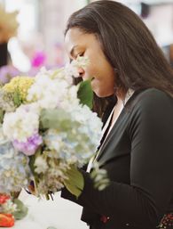 Close-up of a florist arranging a colorful hydrangea bouquet indoors in a flower shop, woman trimming stems and shaping blooms.