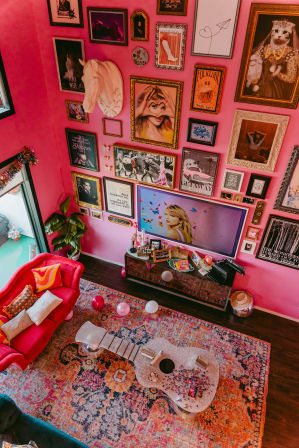 Bright pink boho living room with an eclectic gallery wall, red velvet sofa, glitter guitar-shaped coffee table, colorful patterned rug and balloons.