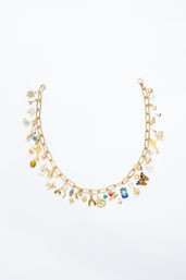 Gold chain charm necklace flat-lay on white background — fashion jewelry product shot with colorful enamel charms including butterfly, evil eye, key, wishbone, moon and stars.