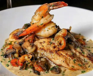 Succulent grilled shrimp perched on a seared fish fillet over creamy mushroom-herb sauce on a white plate — restaurant-style seafood entrée
