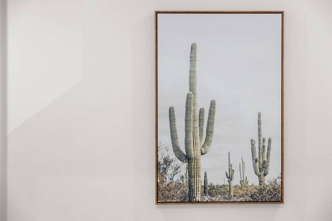 Framed photo of towering saguaro cacti in a desert scene hung on a clean white wall — modern Southwestern home decor.