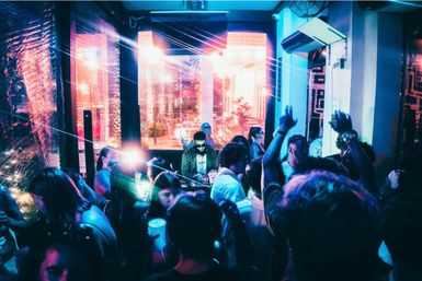 Vibrant neon nightclub scene — DJ spinning at a booth as an energetic crowd dances under colorful laser lights