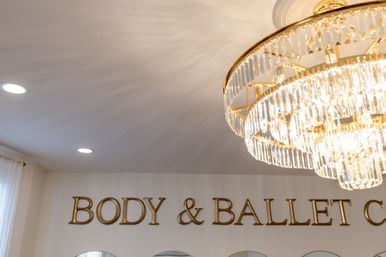 Bright studio interior with sparkling crystal chandelier, recessed ceiling lights, gold wall lettering and mirrored arches