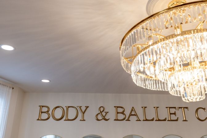 Bright studio interior with sparkling crystal chandelier, recessed ceiling lights, gold wall lettering and mirrored arches