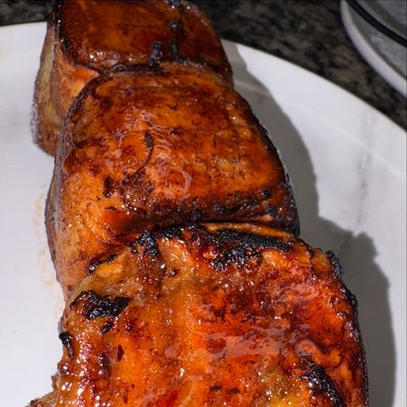 Close-up of three thick caramelized brioche toast cubes with syrupy glaze and charred edges on a white plate, breakfast dessert shot
