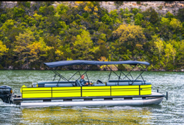 Bright lime-green pontoon boat with black canopy and outboard motor carrying passengers on a scenic tree-lined lake shore