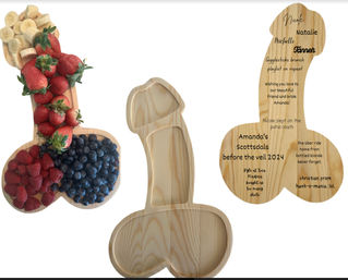 Three wooden penis-shaped charcuterie boards — one loaded with strawberries, blueberries, raspberries and banana slices, one empty, and one engraved with a bachelorette-themed message; playful wooden serving platters for parties.