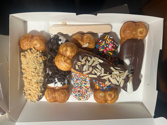 White bakery box of assorted Hong Kong-style bubble egg waffles dipped in chocolate and topped with rainbow sprinkles, crushed cookies, chopped peanuts and sliced almonds