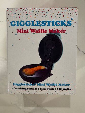 Packaging for a playful mini waffle maker with sprinkle-pattern background, open waffle iron imprinting a novelty-shaped waffle; 4-inch cooking surface, non-stick, 350 watts.