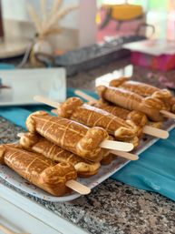 Golden-brown waffle pops on wooden sticks stacked on a tray over a granite kitchen counter – playful party dessert display