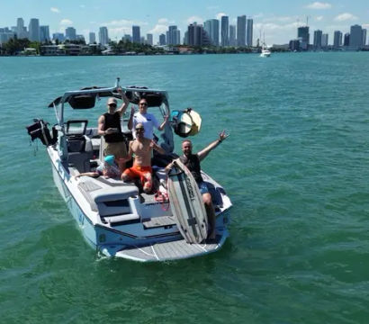 Friends on a wakeboarding boat in turquoise water with the Miami skyline and sunny blue sky