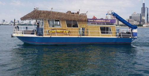 Tropical-themed party boat with a thatched roof and blue waterslide on Lake Michigan with the Chicago skyline in the background