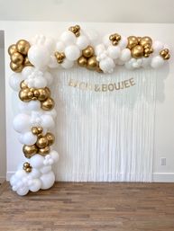White and gold balloon garland framing a white fringe photo backdrop on hardwood floor, featuring gold 'BACH & BOUJEE' letters — elegant bachelorette party decor.