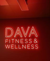 Red neon wall sign reading Fitness & Wellness glowing against a red studio interior, modern boutique gym vibe.