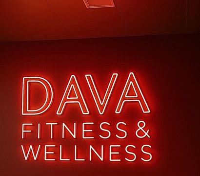 Red neon wall sign reading Fitness & Wellness glowing against a red studio interior, modern boutique gym vibe.