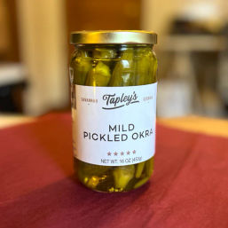 Jar of mild pickled okra — bright green spears in brine inside a 16 oz glass jar with a gold lid, sitting on a red tablecloth