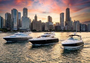 Three luxury yachts cruising on golden Lake Michigan at sunset with the Chicago skyline and a dramatic pink-orange sky.
