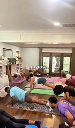 Energetic group workout doing plank exercises on colorful yoga mats in a bright home living room with hardwood floors and glass doors, with the word "purpose." overlaid.