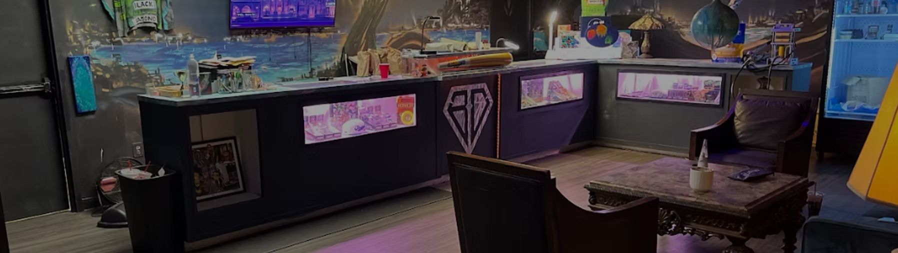 Cozy neon-lit indoor lounge with a long glass display counter beneath a colorful mural, plush armchairs around a carved wooden coffee table, ambient lamps and modern decor