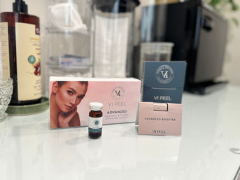 VI Peel skincare kit and advanced booster vials displayed on a glossy white spa countertop with a blurred dispenser and tissue holder in the background
