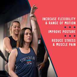 Trainer-assisted overhead arm stretch in a fitness studio — woman improving flexibility, posture, and easing muscle pain.