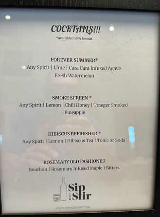 Framed bar cocktail menu on white paper listing four drinks: Forever Summer (any spirit, lime, cara cara infused agave, fresh watermelon); Smoke Screen (any spirit, lemon, chili honey, smoked pineapple); Hibiscus Refresher (any spirit, lemon, hibiscus tea, tonic or soda); Rosemary Old Fashioned (bourbon, rosemary‑infused maple, bitters).