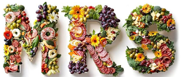 Colorful charcuterie letter art spelling MRS made from cured meats, cheeses, grapes, olives, crackers and edible flowers on a white background — creative food typography for parties and events.