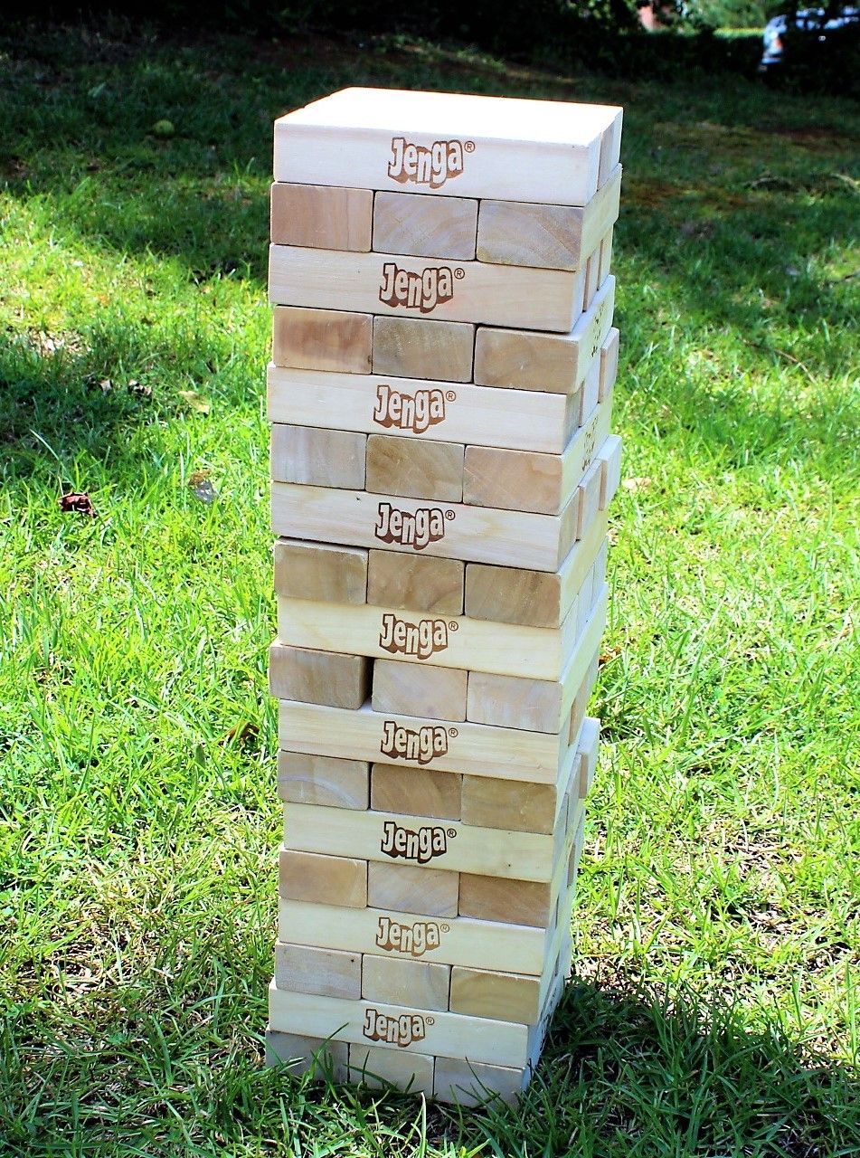 Giant stacked wooden block tower game set up on a sunny backyard lawn