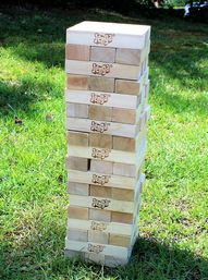 Giant stacked wooden block tower game set up on a sunny backyard lawn