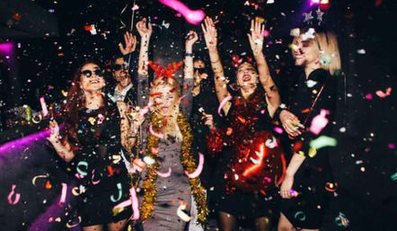 Group of people dancing under flying confetti and colorful lights at a lively nightclub party with balloons and drinks—energetic urban nightlife celebration