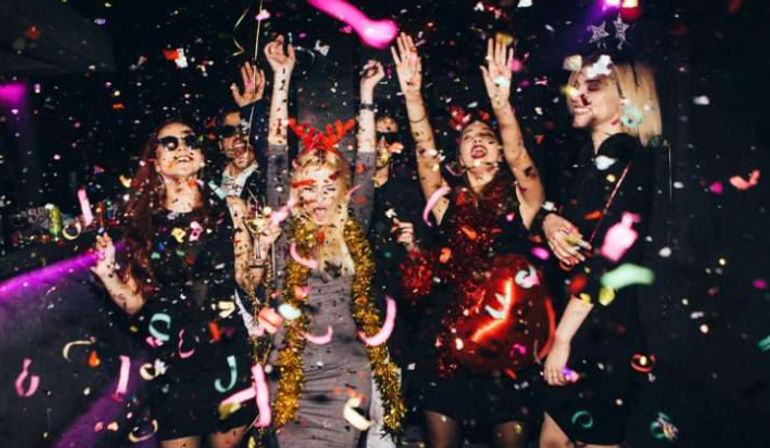 Group of people dancing under flying confetti and colorful lights at a lively nightclub party with balloons and drinks—energetic urban nightlife celebration