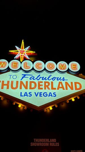 Retro neon welcome sign topped by a glowing star, with illuminated 'Las Vegas' text against a black night sky
