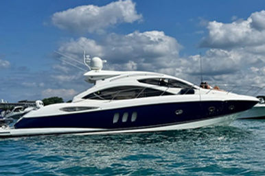 Sunlit luxury blue-and-white motor yacht on turquoise water beneath a partly cloudy sky