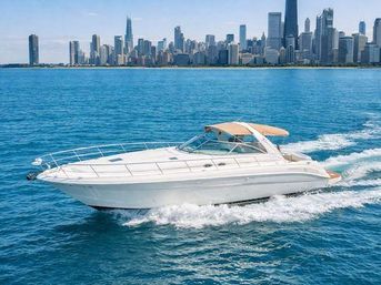 White motor yacht speeding across bright blue Lake Michigan waters with the Chicago skyline of skyscrapers along the waterfront under a clear sunny sky