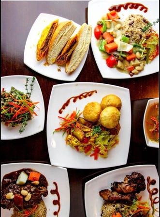Overhead view of assorted plated restaurant dishes on white square plates: sliced sandwiches, colorful vegetable curry with rice, mixed salad, three golden puff pastries with sautéed veggies, braised beef stew and grilled chicken with rice, all garnished with vibrant carrot ribbons and sauce swirls.