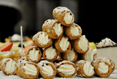 Tower of ricotta-filled Italian cannoli, crispy pastry shells piped with creamy filling and dusted with powdered sugar on a dessert table