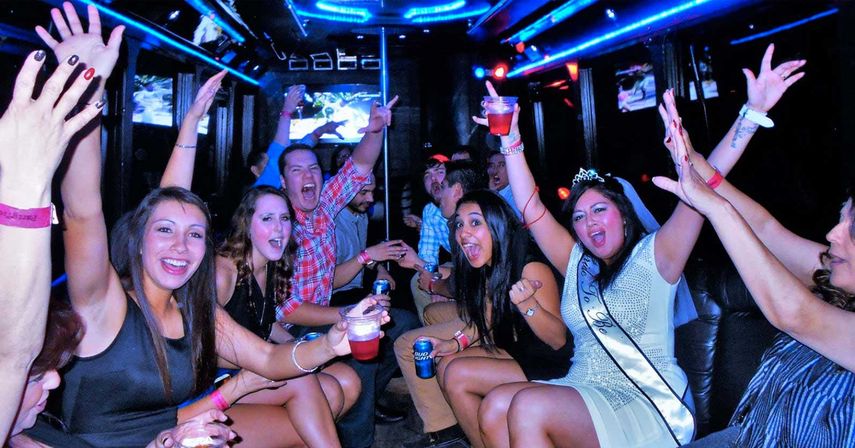 Energetic bachelorette party on a neon-lit party bus, friends cheering with drinks, bride-to-be wearing a tiara and sash.