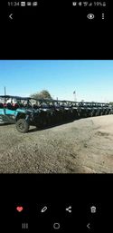 Long row of side-by-side UTVs parked on a gravel lot under a clear blue sky, ready for off-road desert tours