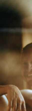 Close-up vertical crop of a hand resting on a thigh in warm, soft-focus indoor light, relaxed cozy mood with blurred background.