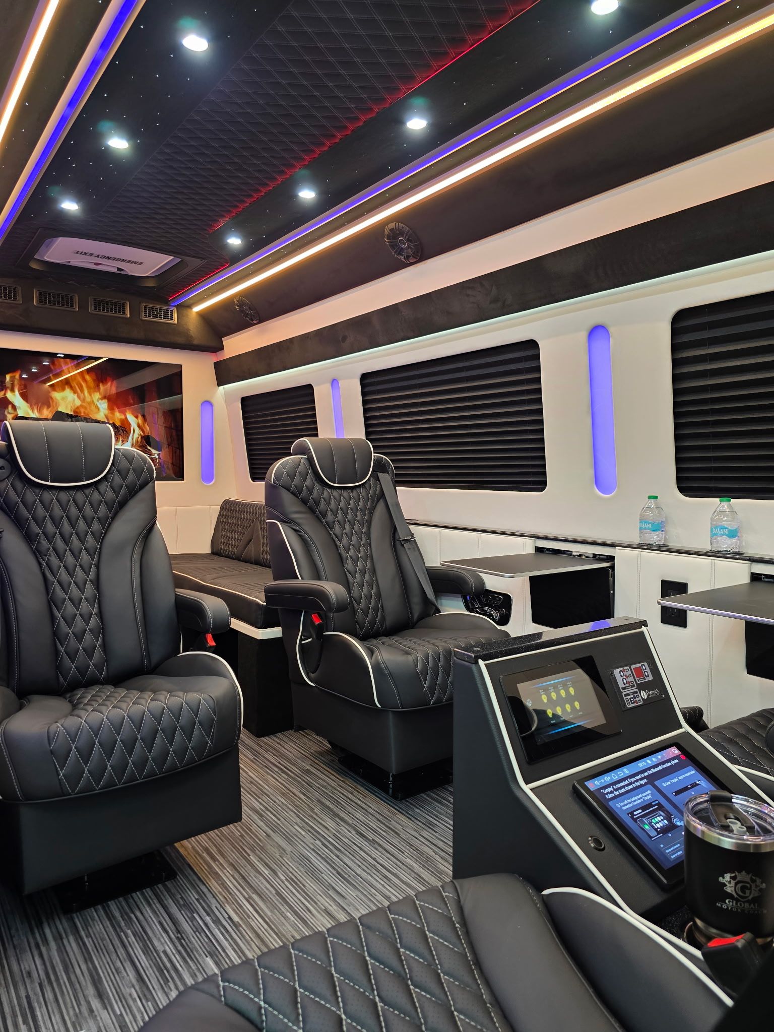 Sleek luxury van interior with quilted black leather captain chairs, ambient multicolor LED ceiling lights, touchscreen control panels and cup holder — modern executive shuttle cabin