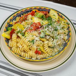 Italian-style fusilli pasta with yellow squash, red bell pepper, parsley and grated Parmesan in a colorful bowl — bright summer vegetable pasta