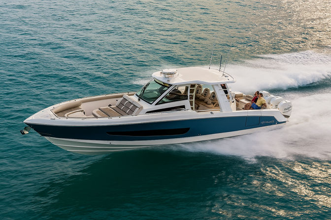 Sleek blue-and-white luxury powerboat cruising at speed across turquoise sea, white wake trailing and passengers seated near the stern