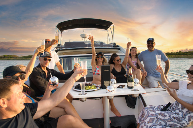 Friends toasting champagne on a luxury yacht at sunset during a coastal cruise with a fruit platter