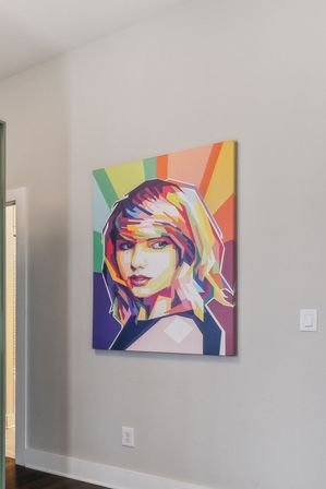 Vibrant geometric pop-art canvas portrait of a woman with rainbow rays, hanging on a light-gray wall in a modern home hallway