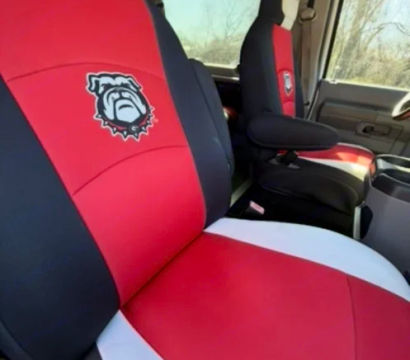 Truck interior with custom red, black and white seat covers featuring a bold bulldog emblem and partial "GEO" lettering on the front bench and captain’s seat